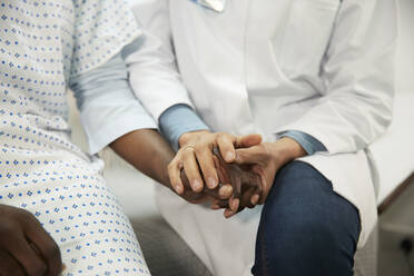 Arzt hält die Hände eines Patienten im Krankenzimmer - PMF02239
