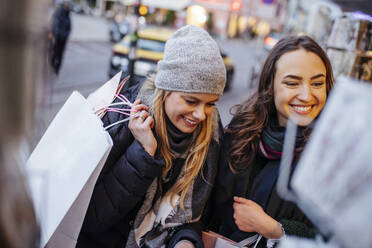 Glückliche Freunde schauen durch das Schaufenster eines Geschäfts auf dem Weihnachtsmarkt - DAWF02425