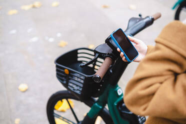 Frau nutzt Smartphone, um Elektrofahrrad zu mieten - AMWF00074