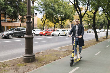 Man riding electric push scooter on street in city - JRVF02427