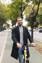 Bärtiger Mann mit Elektro-Scooter auf dem Fahrradweg - JRVF02429