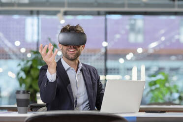 Geschäftsmann mit VR-Brille gestikuliert im Büro - EIF03076