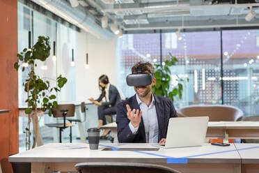 Employee with VR googles gesturing in office - EIF03078