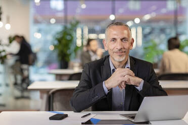 Businessman with hands clasped in office - EIF03100