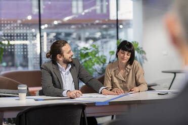 Businessman discussing with colleague over paper document in coworking space - EIF03101