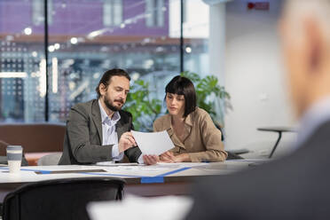 Manager diskutiert mit einem Kollegen über ein Papierdokument im Büro - EIF03102