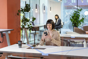 Textnachrichten des Managers auf dem Smartphone am Schreibtisch im Büro - EIF03109