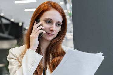 Arbeitende Frau, die über Dokumente auf einem Smartphone im Büro diskutiert - SSGF00466