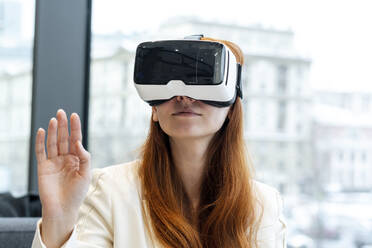 Geschäftsfrau mit Virtual-Reality-Headset gestikuliert im Büro - SSGF00476