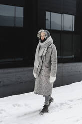 Frau in warmer Kleidung auf schneebedecktem Fußweg - SEAF00344