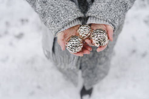 Woman holding silver sphere balls at winter - SEAF00352