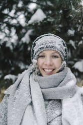 Glückliche Frau mit verschneiter Strickmütze in einem öffentlichen Park - SEAF00395