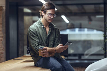 Geschäftsmann mit Smartphone auf dem Schreibtisch in einem Coworking-Büro - JSRF01801