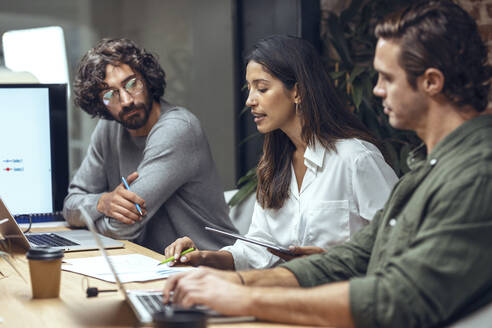 Businesswoman explaining business strategy to colleagues on document in meeting at office - JSRF01819