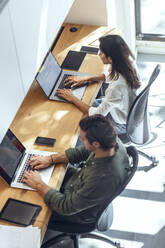 Geschäftsmann und Geschäftsfrau mit Laptops am Schreibtisch in einem Coworking-Büro - JSRF01830