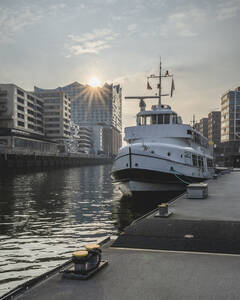 Deutschland, Hamburg, Boot im Sandtorhafenkanal mit Sonnenuntergang über der Elbphilharmonie im Hintergrund - KEBF02122