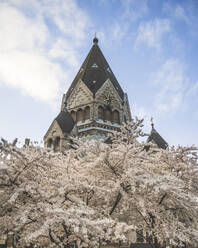 Deutschland, Hamburg, Glockenturm der Kirche St. Johannes von Kronstadt mit blühenden Kirschblüten im Vordergrund - KEBF02131