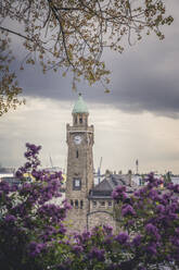 Germany, Hamburg, Clock tower in Saint Pauli Piers with blooming flowers in foreground - KEBF02154