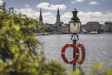 Germany, Hamburg, Life belts hanging on street light standing on shore of Inner Alster Lake - KEBF02169