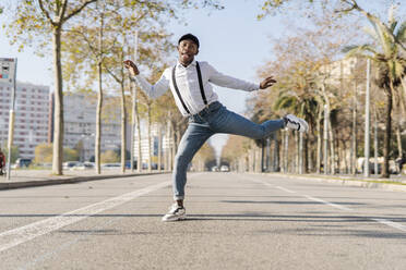 Junger Mann mit Mütze tanzt auf der Straße in der Stadt - JCZF00930
