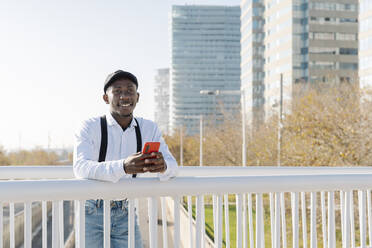 Smiling young man with mobile phone in city - JCZF00943