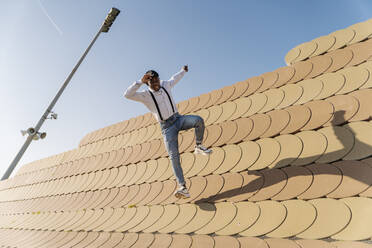 Young man jumping over roofing tiles on sunny day - JCZF00959