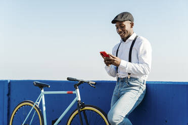 Lächelnder Mann mit Fahrrad und Smartphone - JCZF00961