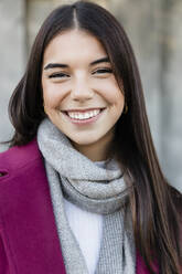 Happy young woman with long brown hair wearing scarf - JRVF02487