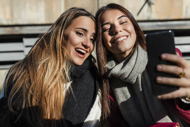 Happy friends taking selfie together through smart phone on sunny day - JRVF02490