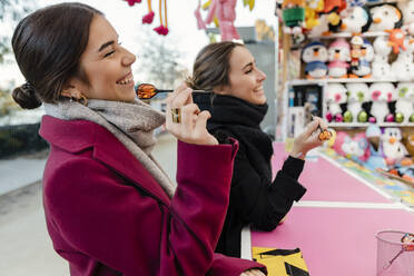 Glückliche Freunde spielen Dartspiel am Straßenmarktstand - JRVF02504