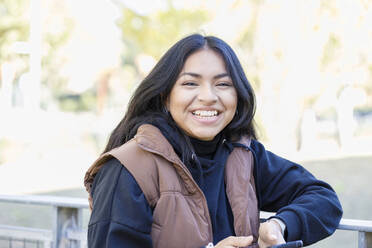 Cheerful woman with jacket on campus - IFRF01409