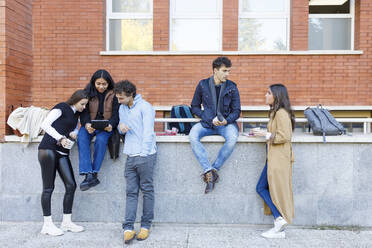 Multiracial students discussing on project by wall on campus - IFRF01455