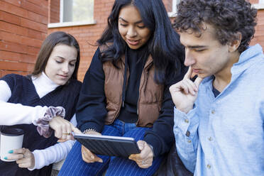 Frau teilt Tablet-PC mit Freunden auf dem Universitätscampus - IFRF01457