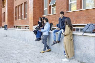 Multiracial students discussing on project by college building - IFRF01458