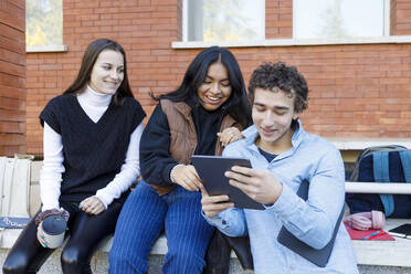 Mann teilt Tablet-PC mit Freunden auf dem Universitätscampus - IFRF01460