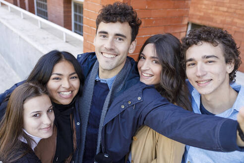 Smiling multiracial friends taking selfie at university campus - IFRF01466