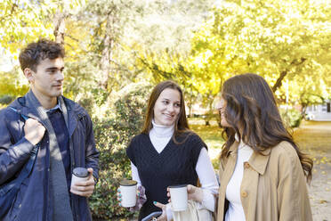 Friends with disposable coffee cup talking in college park - IFRF01468