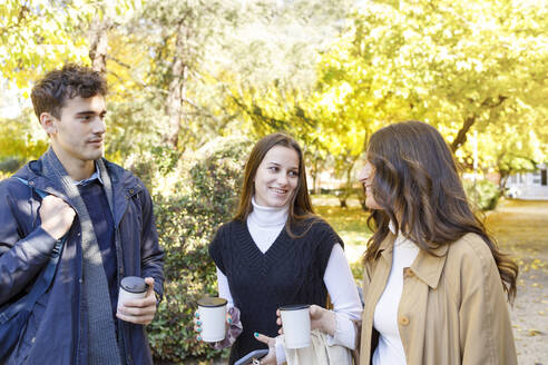 Friends with disposable coffee cup talking in college park - IFRF01468