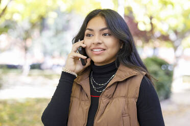 Junge Studentin, die im College-Park mit ihrem Smartphone telefoniert - IFRF01479
