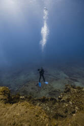 Woman scuba diving over ocean floor in blue sea - RSGF00838