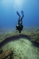 Young man diving upside down over ocean floor in sea - RSGF00846