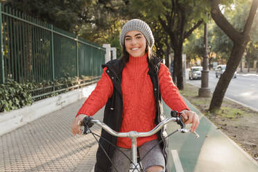 Lächelnde schöne Frau mit Fahrrad auf der Straße - JRVF02511