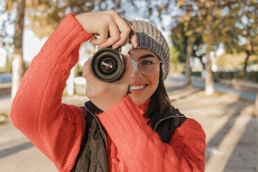 Smiling woman photographing through camera - JRVF02521