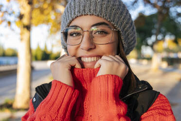 Lächelnde junge Frau mit Sonnenbrille und Strickmütze - JRVF02527