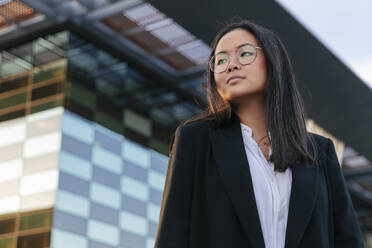 Thoughtful working woman in front of office building - JRVF02571