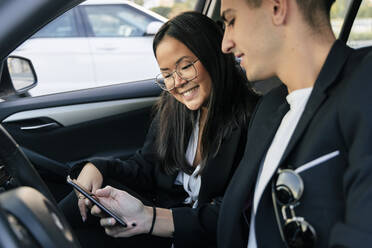 Geschäftskollegen teilen sich ein Smartphone im Auto - JRVF02579