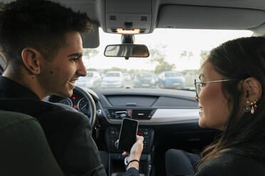 Young business colleagues looking at each other sitting in car - JRVF02580