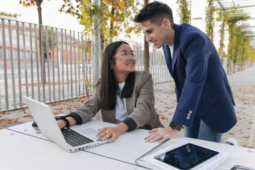 Business colleagues discussing over laptop at table - JRVF02611