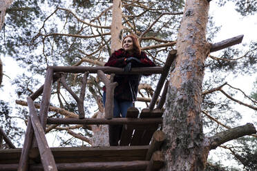 Woman day dreaming at tree house in forest - JCCMF05232