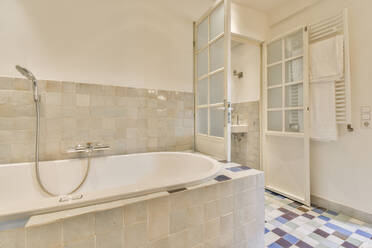 Zeitgenössisches Badezimmerinterieur mit Badewanne in einer stilvollen Wohnung in der Tageszeit - ADSF33258
